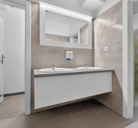 Offices with ceramic tiles, double sink, and large mirror.