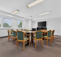 Conference room with windows, television, and a table with multiple chairs in an office.