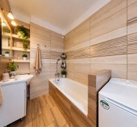 Bathroom with a bathtub, sink, and plants in a 3-room apartment, floor with wood decor.