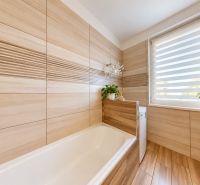Bathroom with a bathtub and a window, floor with wooden decor, 3-room apartment.