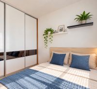 A bright bedroom in a 3-room apartment with a large wardrobe and plant decor.