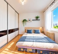 A bright bedroom with a bed and a large wardrobe in a 3-room apartment, floor with wooden decor.