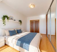 Bright bedroom in a 3-room apartment with a bed, wood-patterned flooring, and a mirrored wardrobe.