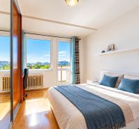Bright bedroom with a bed, mirrored wardrobe, and wooden decor flooring.
