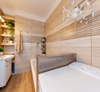 A bathroom in a 3-room apartment with a wooden decor floor, a bathtub, and a washing machine.