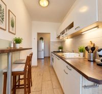 A kitchen in a 3-room apartment with wooden decor and plants on the table.