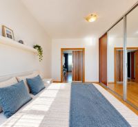Bedroom in a 3-room apartment with a large bed and a mirrored wardrobe, wooden decor flooring.