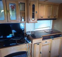Interior of a caravan with wooden decor cabinets and electronics on the floor.