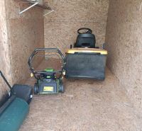 A wooden shelter with garden equipment including lawnmowers in the gardens.