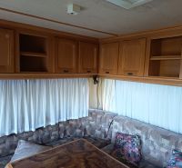 The interior of a caravan with a sofa, cabinets, and curtains, gardens, decorative table.