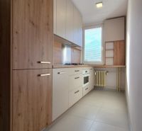 A kitchen in a studio apartment with a wood decor and built-in appliances.