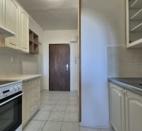 A kitchenette in a studio apartment with a white kitchen unit and ceramic flooring.