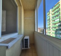 Enclosed balcony in a studio apartment with air conditioning and a view of the apartment buildings.