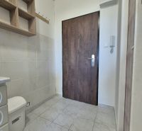 Studio apartment with a tiled floor, wooden shelf, and door with a wooden decor.