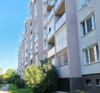 The exterior of a panel building in Trnava with greenery and a walkway to a 3-room apartment.