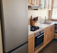 A kitchen unit in a 3-room apartment with wooden cabinets and appliances.