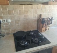 A kitchen unit with a hob and extractor in a 3-room apartment, tiled with tiles.
