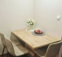 Dining area in a 3-room apartment with a wooden decor floor and decorations.