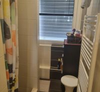 A bathroom with a tiled shower, curtain, and window in a 3-room apartment.