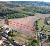 A view of agricultural and forest land in Podhájska, surrounded by houses and roads.