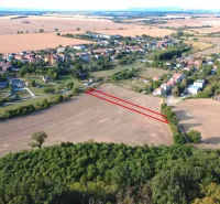 Aerial view of agricultural and forest lands in Podhájska, with the village in the background.