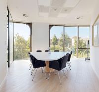 A dining area in offices with a wood-patterned floor and large windows.