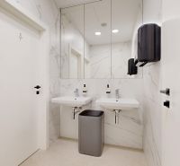Modern bathroom in offices with two sinks, a mirror, and marble tiles.