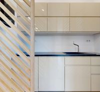A kitchen unit with beige cabinets and a black countertop in the office.