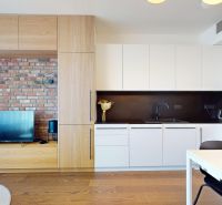 A kitchen in a 2-room apartment with a brick wall and a wooden decor floor.