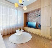 Living room in a two-room apartment with brick cladding, a window, and a floor with a wooden decor.