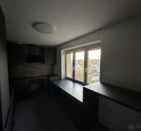 A kitchen in a 2-room apartment with dark furniture and a view from the window.