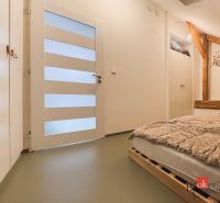 A bedroom with wooden elements, a pallet bed, and storage space in a three-room apartment.