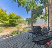 A terrace in a 3-room apartment with wooden decor, a garden, and outdoor seating.