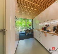 A kitchen in a 3-room apartment with a wooden ceiling and large glass windows.