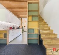 A kitchen with white cabinets and a wooden decor floor in a 3-room apartment.