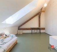 Attic room with a bed, wood-patterned floor, and a skylight in a 3-room apartment.