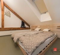 An attic bedroom with wooden elements and a double bed in a three-room apartment.