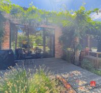 A terrace with greenery, wooden decor, and garden seating of a 3-room apartment.