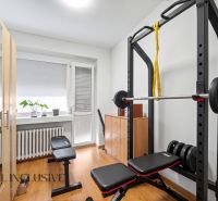 Home gym with a bench, dumbbells, and a wooden decor floor.