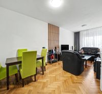 Living room with black sofas, dining table, and floor with wood decor.