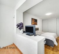 A bright bedroom with a TV, bed, and wood-decor flooring in a family house.