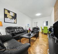 Living room in a family house with black leather furniture and a wooden decor floor.