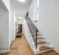 A staircase with white walls and a wood-patterned floor in a family house.