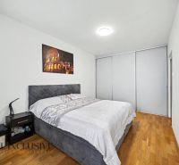 Bedroom with a large bed, a nightstand, and a wooden decor floor in a family house.