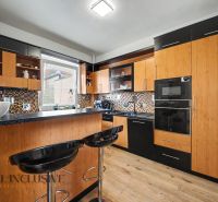A kitchen with black furniture and a wood-patterned floor in a family house.