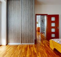 Bedroom in a 4-room apartment with wood-patterned flooring and a spacious wardrobe.