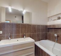 A bathroom with a light sink and bathtub in a 4-room apartment, complemented by brown tiles.
