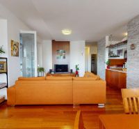 A living room with light elements, a leather sofa, and a floor with a wooden design.