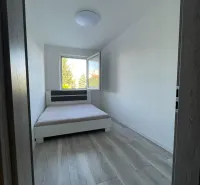 A bedroom with a bed and a wooden decor floor in a two-room apartment.