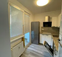 A kitchen in a 2-room apartment with a wooden decor floor, white cabinets, and a built-in appliance.
